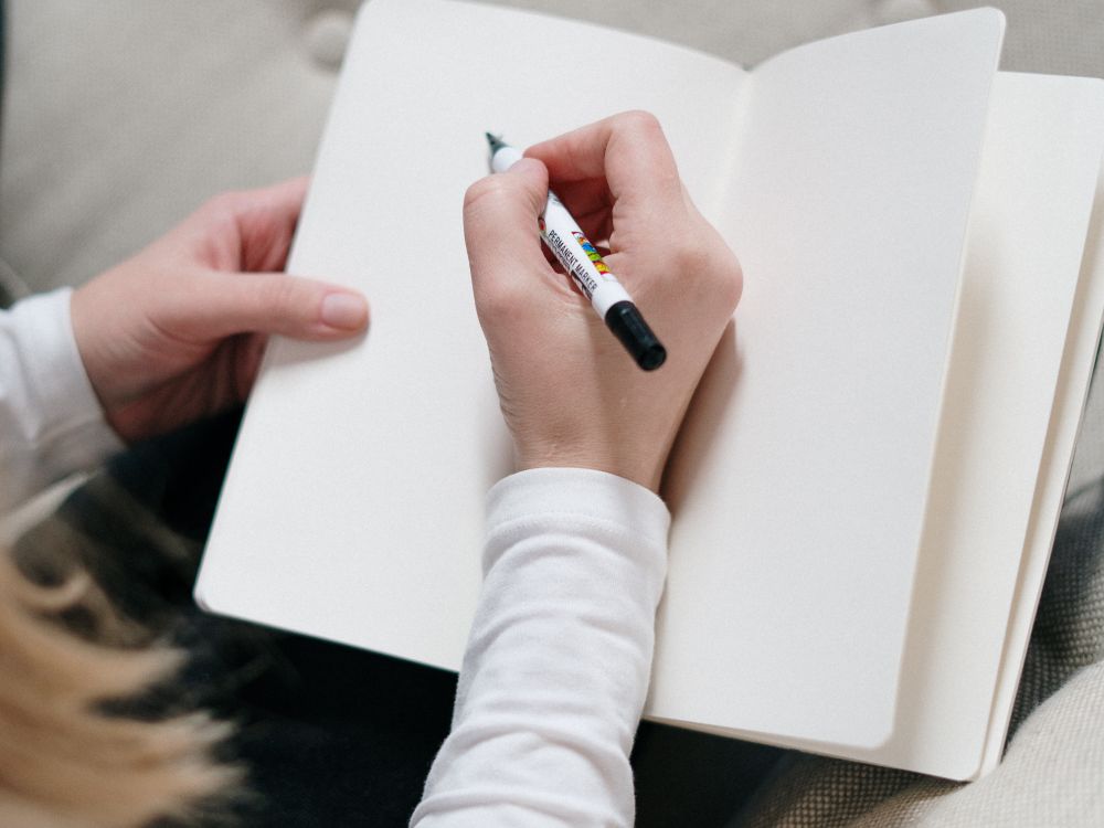 A person writing in a journal at a calm desk